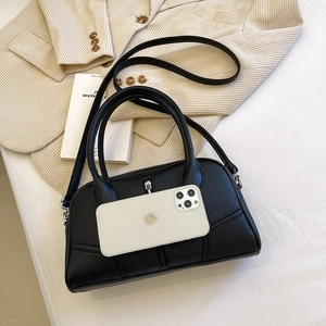 Detail of black lychee grain leather handbag with dual round handles and vertical zippers