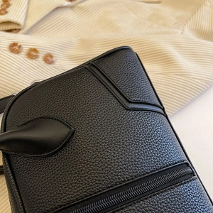 Close-up of black lychee grain leather texture and smooth zipper detail on shoulder bag