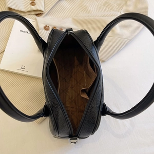 Top view of black pebbled leather handbag with spacious interior and brown lining