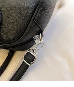 Detail of adjustable shoulder strap with silver metal buckle on black lychee leather bag