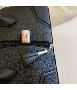 Detail of the black lychee pattern leather bag showing a zipper pocket with a lipstick inside