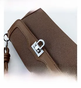 Close-up of the silver-tone metal rotating lock and brown woven leather texture on a bag