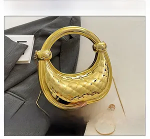 Détail de la poignée anneau dorée et texture matelassée sur pochette de soirée luxe