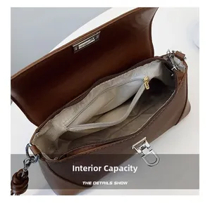Detailed interior of brown textured leather shoulder bag with zipper pocket and metal clasp