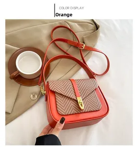 Detail of orange crossbody bag with herringbone weave flap and golden metal clasp lock