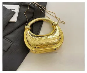 Vue détaillée de la pochette matelassée dorée avec poignée ronde et bandoulière chaîne