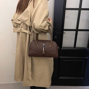 Detail of dark brown lychee leather handbag featuring curved stitching and silver zipper tassel