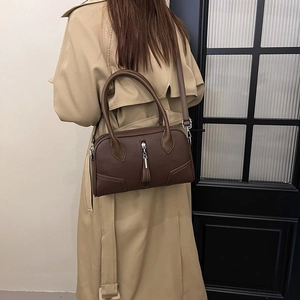 Detail of a dark brown lychee leather handbag worn with a classic khaki trench coat