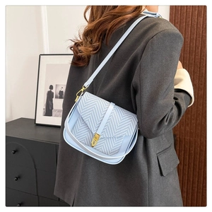Minimalist light blue woven crossbody bag with metal buckle shown on model