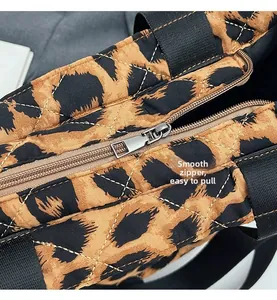 Close-up of quilted leopard print fabric with a smooth silver metal zipper and black strap
