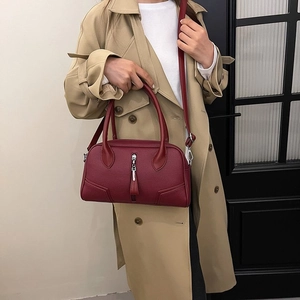 Close-up of wine red lychee pattern leather bag with silver zipper on khaki trench coat
