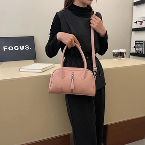 Detailed view of pink lychee leather handbag with tassel zipper and detachable strap