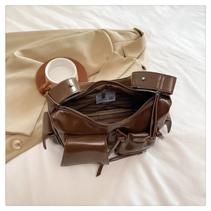 Sac moto en similicuir marron à poches multiples sur fond beige pour un style urbain