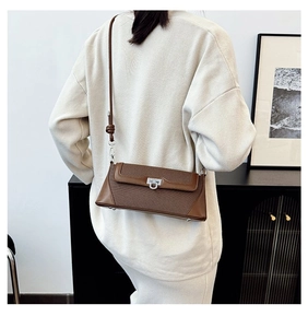 Detail view of brown shoulder bag with silver lock and decorative knot on strap