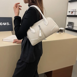 Detail of cream Boston bag with pebble leather texture and vertical zipper on model