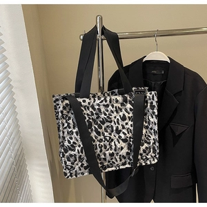Detail of quilted leopard print tote bag featuring black wide handles and metal hardware