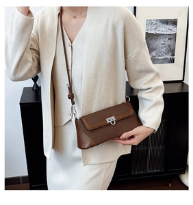 Detail of a brown leather and canvas crossbody bag with a silver U-shaped metal buckle