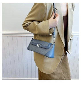 Detail of grey fabric and blue leather paneling with silver U-shaped metal lock on bag