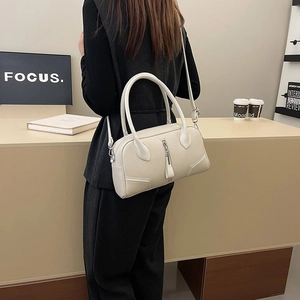 Detail view of cream lychee leather handbag with thick round handles and tassel zipper
