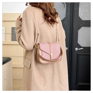 Detail view of pink herringbone pattern on beige leather crossbody bag with gold buckle