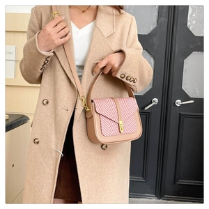 Detail of elegant two-tone shoulder bag featuring pink herringbone weave and gold lock