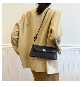 Detailed view of black vintage flap bag with silver clasp worn with a beige blazer