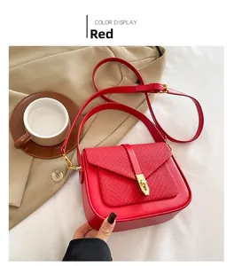 Detail of red leather crossbody bag featuring woven texture and gold metal twist lock