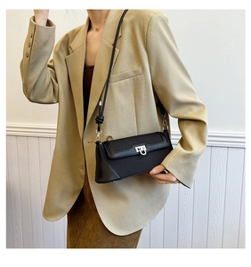Detailed view of black trapezoid crossbody bag with silver U-shaped lock and knotted strap