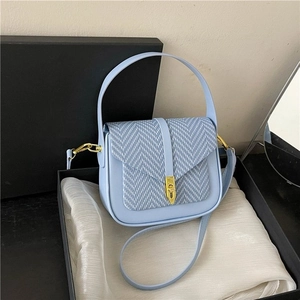Detail of light blue herringbone tweed handbag with gold lock in a premium gift box