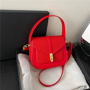 Red crossbody handbag with woven flap and gold buckle on elegant white silk lining