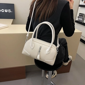 Detail of off-white leather Boston bag with vertical zip and tassel on a model