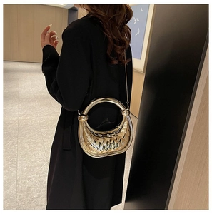 Sac à main doré matelassé avec grandes poignées circulaires en métal porté par un mannequin