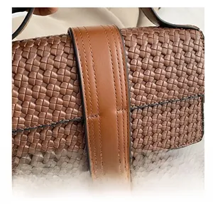 Close-up of woven texture on dark brown shoulder bag with detailed stitching and leather trim