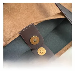 Detail of vintage gold magnetic buckle with geometric texture on brown leather bag