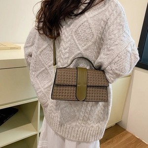 Detail of woven brown texture and olive green leather strap on a stylish crossbody bag