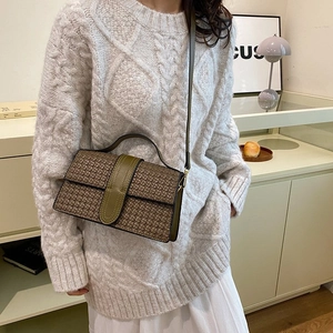 Detailed shot of woven texture shoulder bag with leather strap on a model shoulder