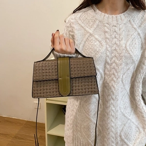 Detail of woven texture handbag with olive green flap and brown leather body