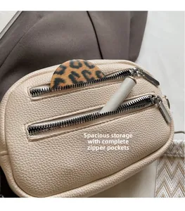 Detail of beige pebbled leather crossbody bag showing dual zipper storage and tiered interior