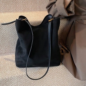Detail of minimalist black suede hobo bag with sleek leather strap on grey texture