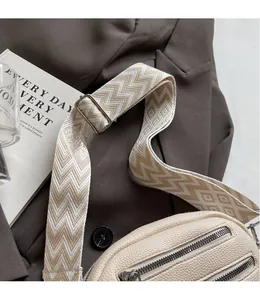 Detail of cream cross-body bag with textured leather and patterned wide shoulder strap