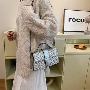 Detail of silver metallic woven texture handbag with sleek magnetic buckle and strap