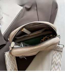 Interior detail of beige small crossbody bag with wide jacquard strap and storage pockets