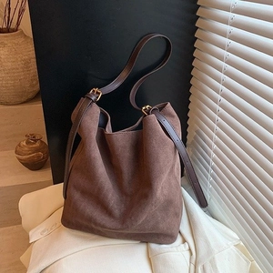 Detail of coffee suede bucket bag showing matte texture and brown leather strap
