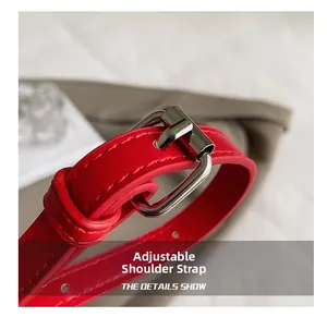 Close-up of adjustable red leather shoulder strap with silver metal buckle and stitching