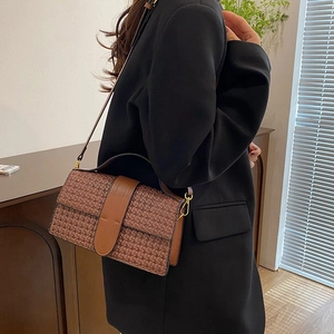 Detailed view of brown woven PU leather shoulder bag with gold hardware and flap closure