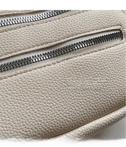 Detail of lychee pattern leather and dual zipper closure on this crossbody round bag