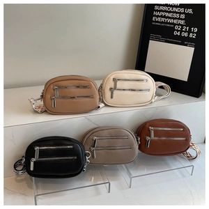 Detail of five oval crossbody bags with textured leather and patterned straps on a white stand