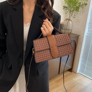 Detail of brown woven shoulder bag with leather buckle strap on an elegant model