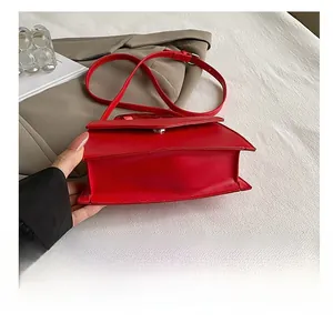 Detail view of the durable base and side structure of a red leather shoulder bag