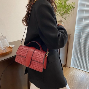 Close-up of red woven leather shoulder bag with gold hardware worn by a model